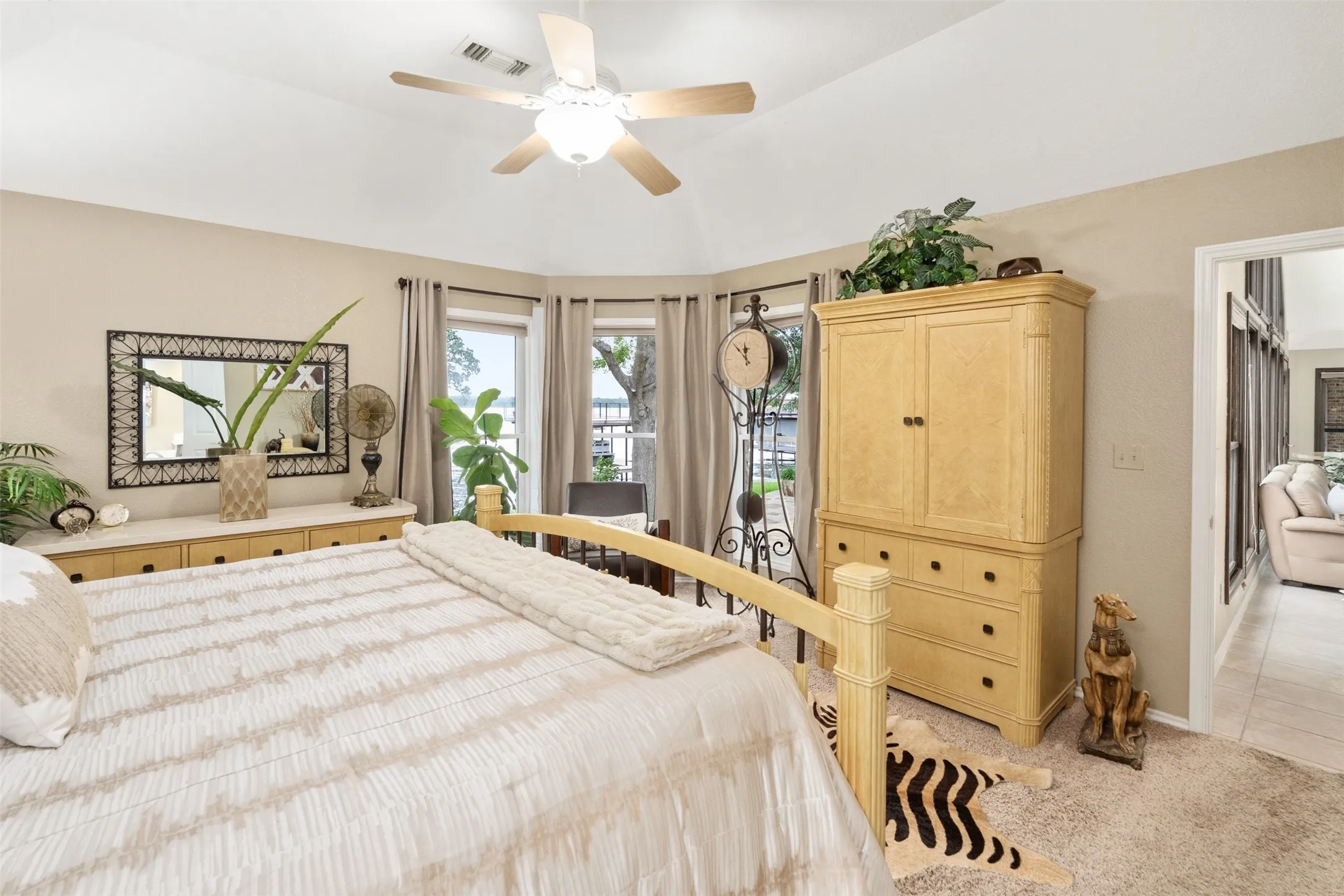 Vaulted ceiling bedroom featuring a bay window, ceiling fan, and neutral-toned carpet flooring