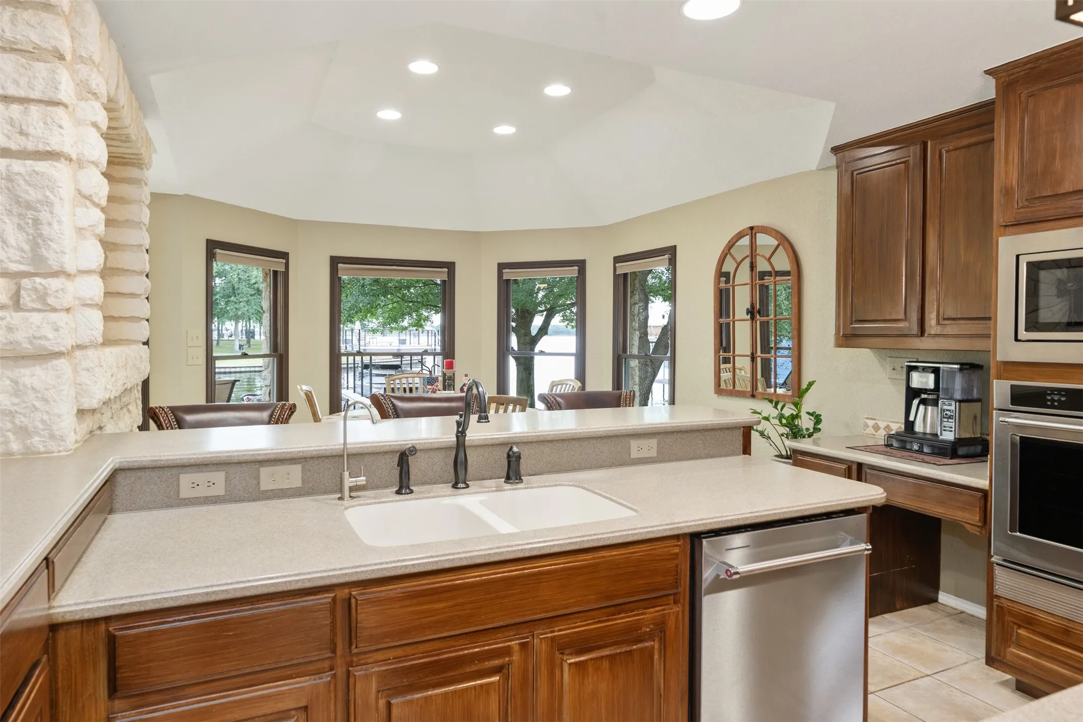 Kitchen featuring a double basin sink, dark wood cabinetry, light-toned countertops, and a built-in stainless steel dishwasher