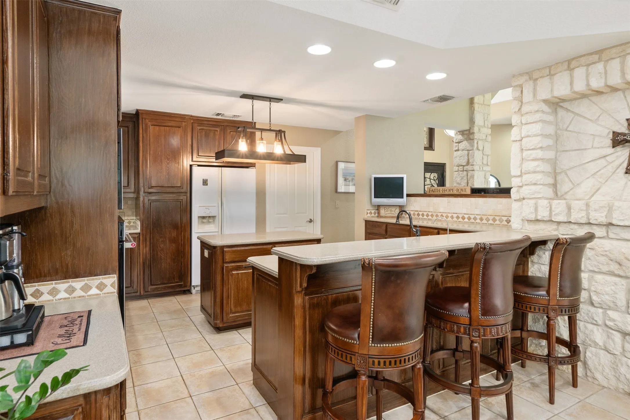 Kitchen featuring dark wood cabinetry, light stone-finish countertops, and ceramic tile flooring
