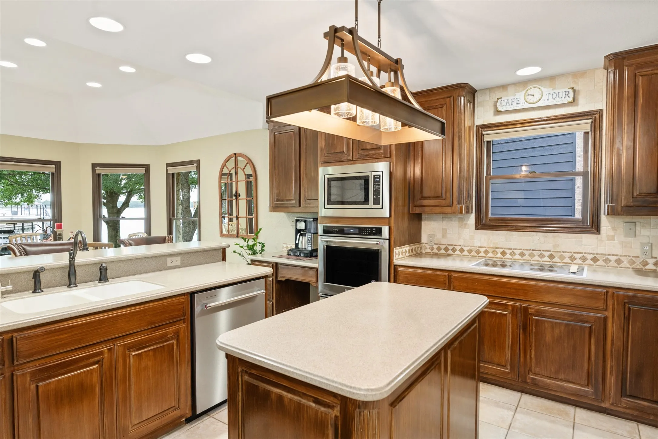 Kitchen featuring wood cabinetry, light-toned countertops, tile flooring, and integrated stainless steel appliances