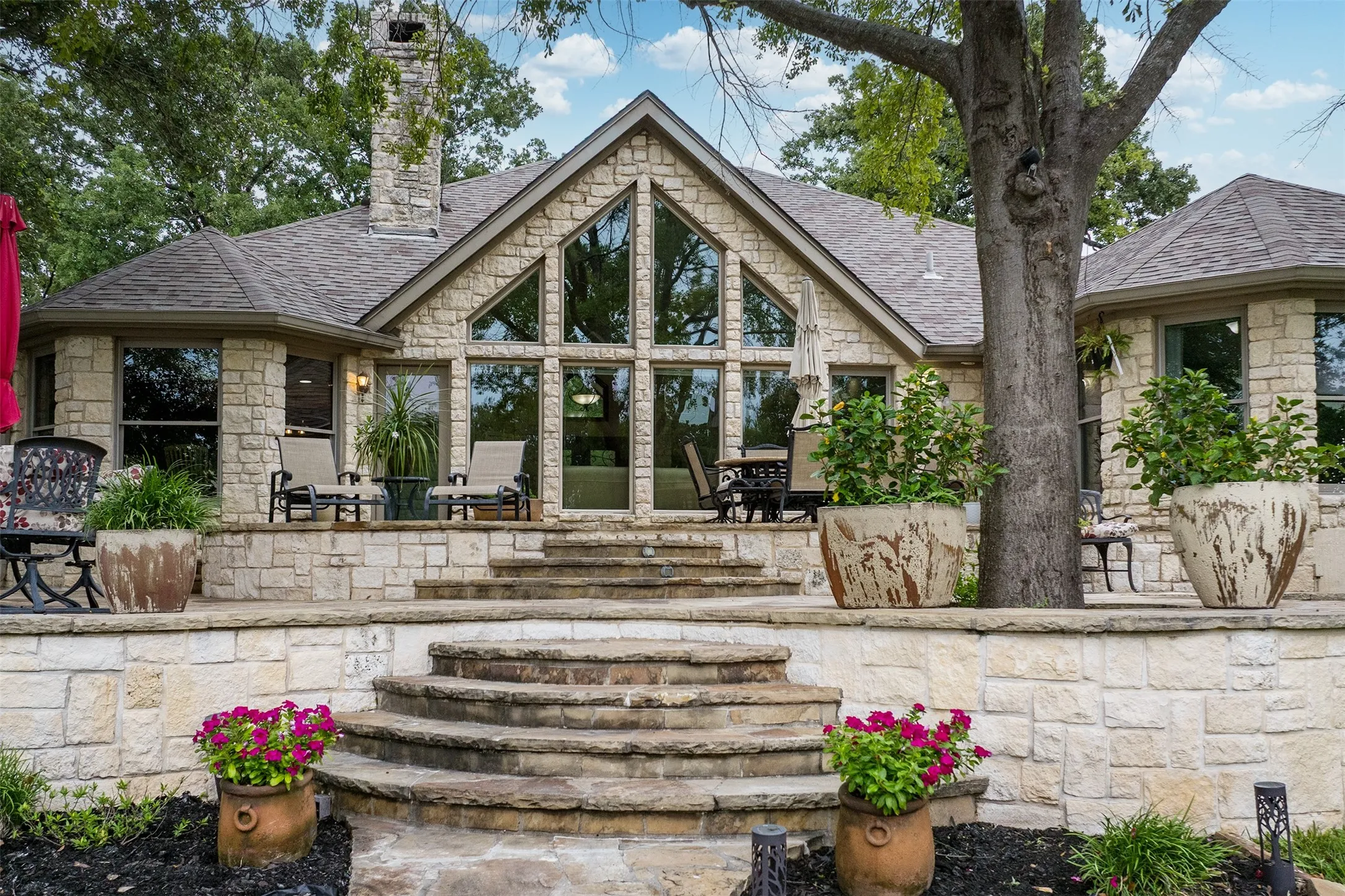 Stone-clad exterior featuring a prominent gabled section with expansive glass panels