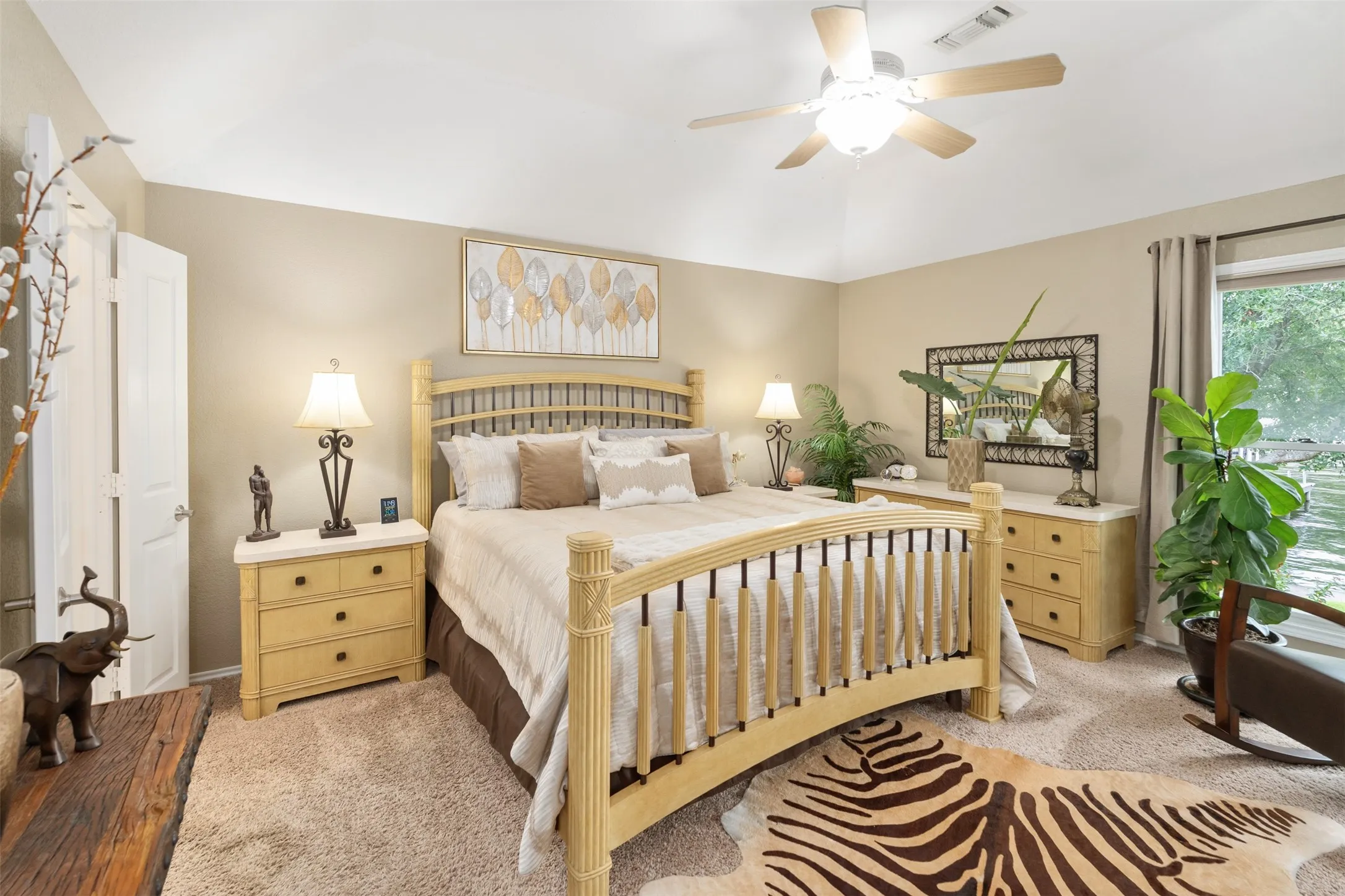 Spacious room featuring vaulted ceilings, a ceiling fan with integrated lighting, broad window, and plush carpet flooring
