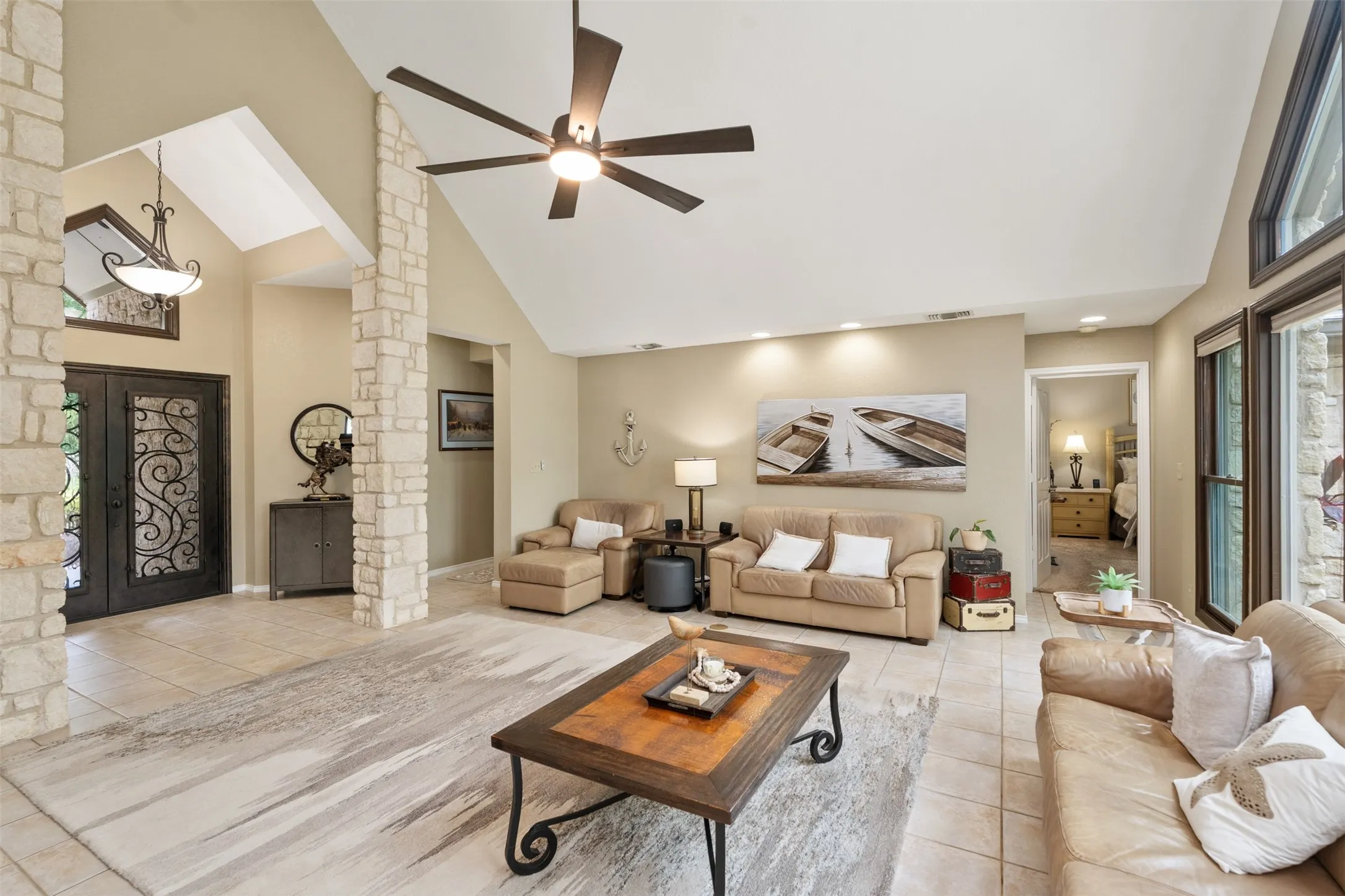 Spacious living area featuring a vaulted ceiling and exposed stone columns
