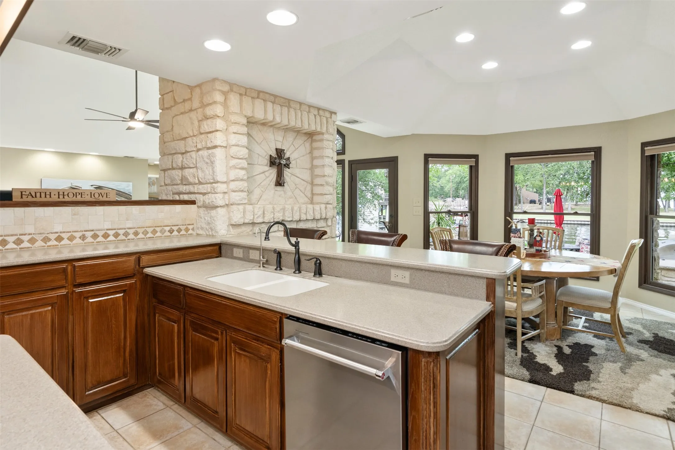 Kitchen featuring warm wood cabinetry, light-colored countertops, and an integrated stainless steel dishwasher