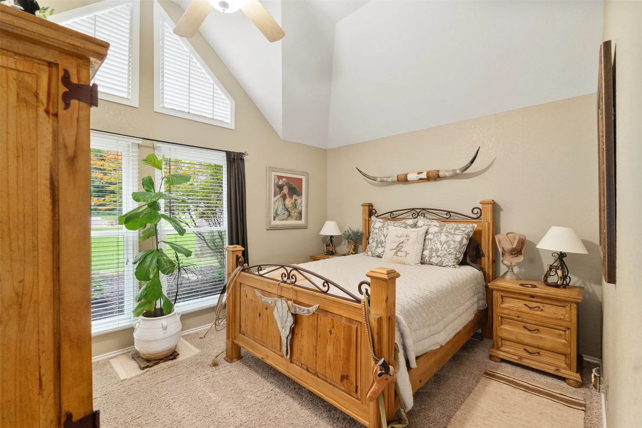 Vaulted ceiling room featuring a ceiling fan, plush carpet flooring, a large window with blinds, and additional accent windows