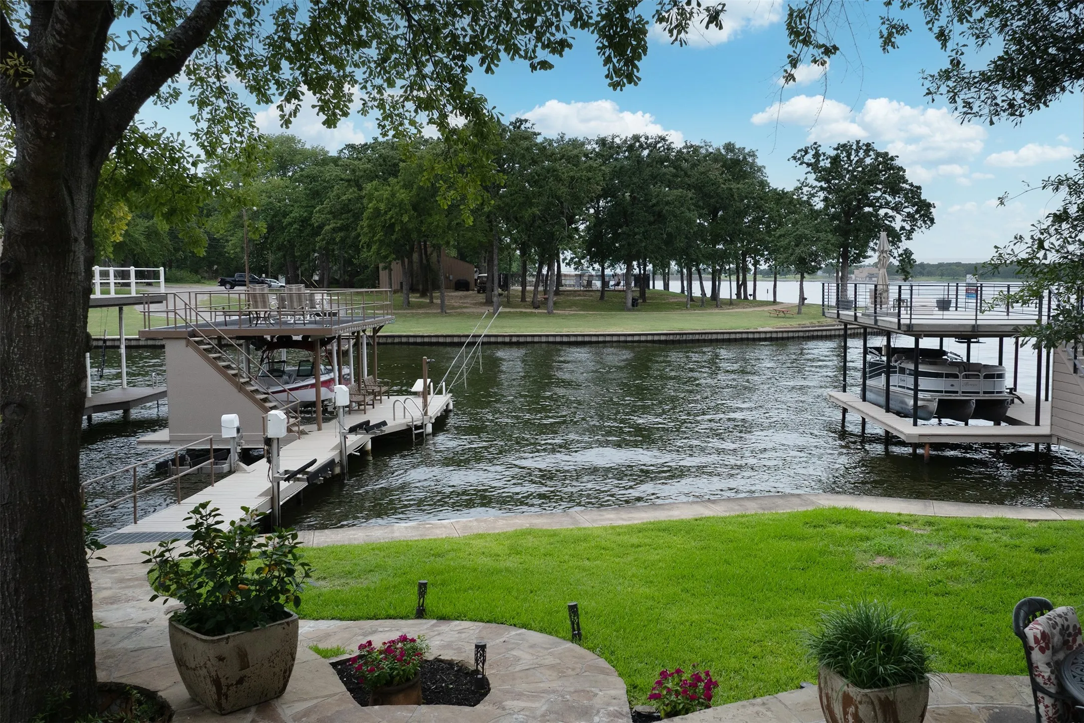 Waterfront property featuring multiple boat docks, a covered boat slip with an upper-level deck, and a secondary open boat slip
