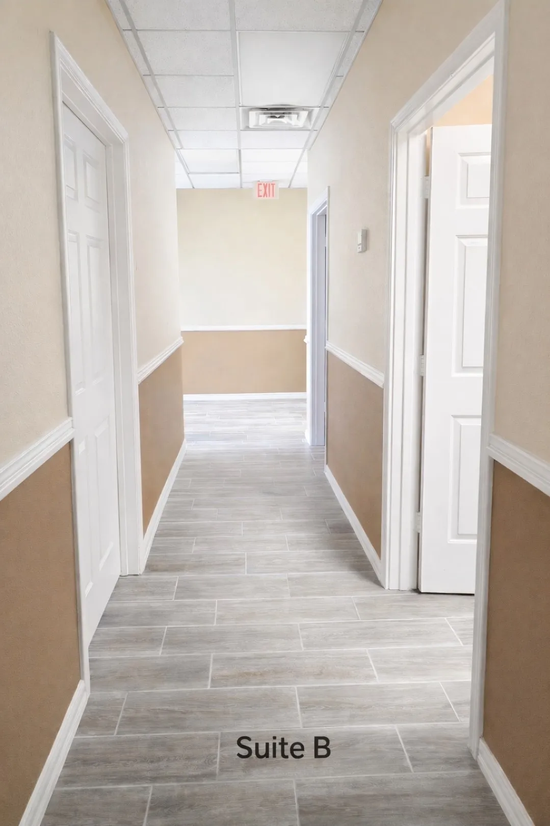 Interior corridor with wood-finish tile flooring, two-tone wall treatment, and white trim