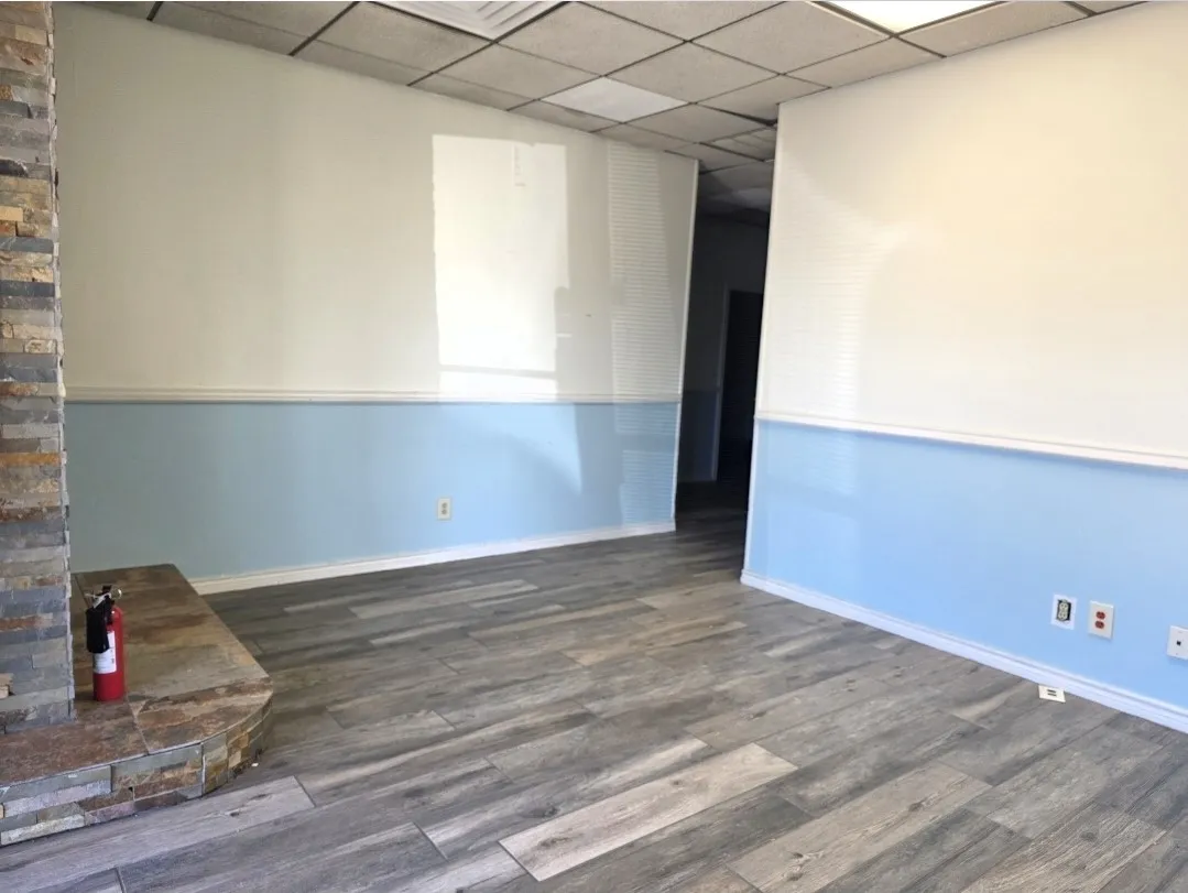 Interior space featuring wood-finish tile flooring, a stacked stone fireplace hearth, and two-tone wall paint with baseboards