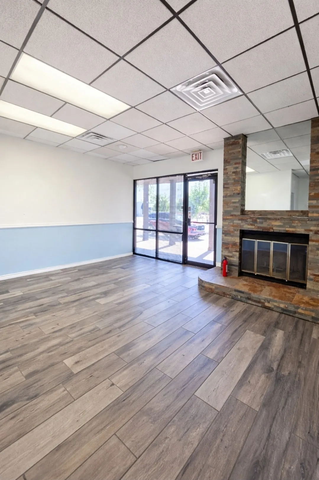 Spacious interior featuring wood-finish plank flooring and a floor-to-ceiling stone-clad fireplace