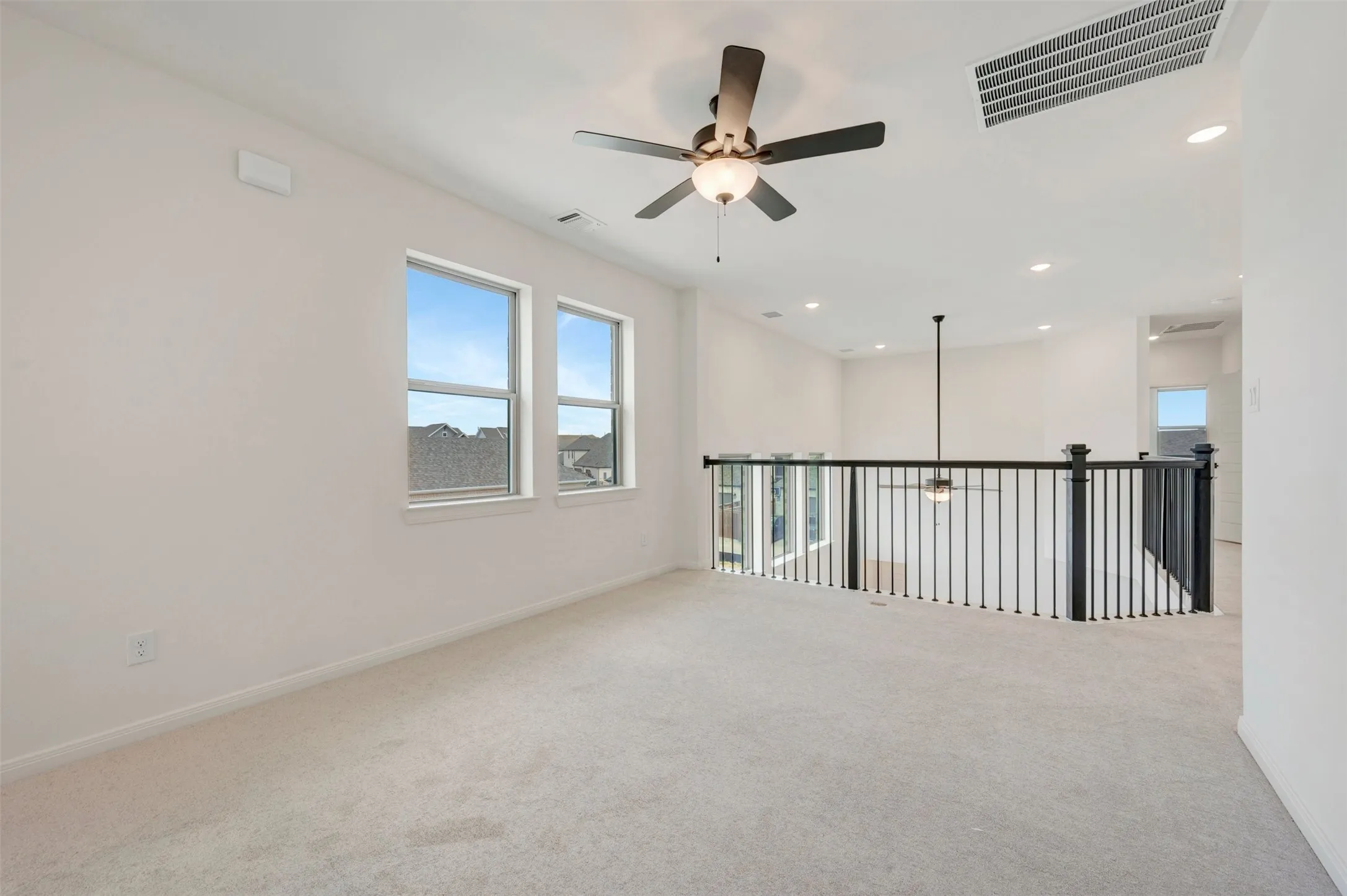 Expansive loft space with abundant natural light, recessed lighting, ceiling fan, and carpet flooring