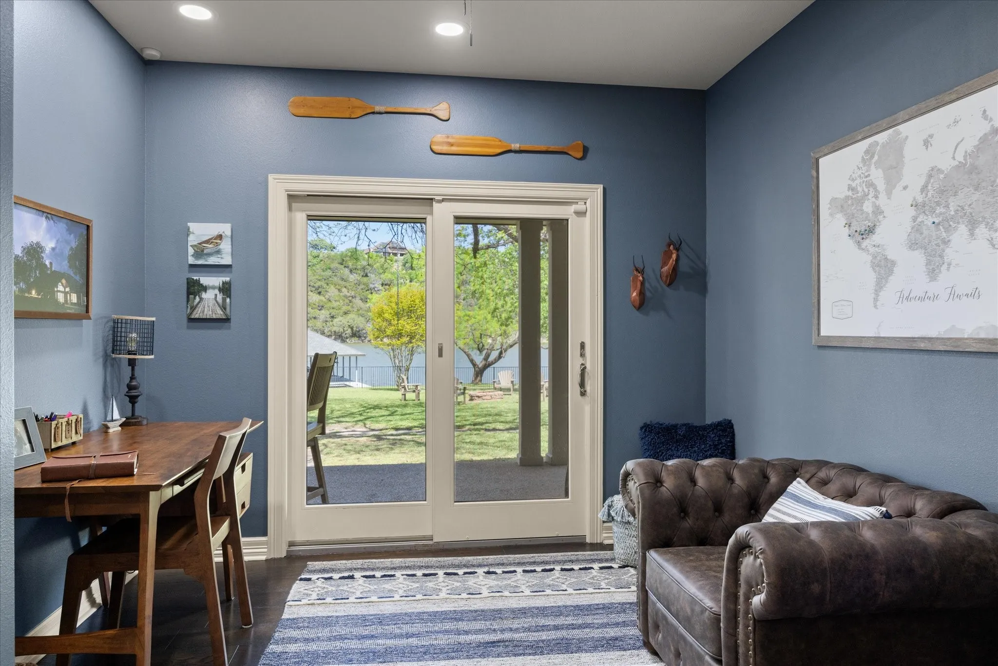 Sliding glass doors opening to an exterior patio area, dark wood-finish flooring, recessed ceiling lighting, and light blue wall paint