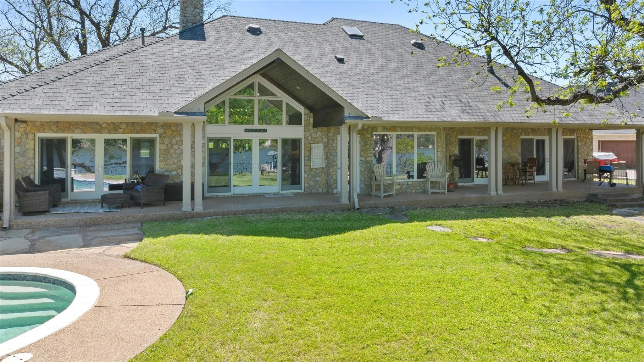 Expansive backyard featuring a manicured lawn, a swimming pool with a hardscape surround, and a covered patio