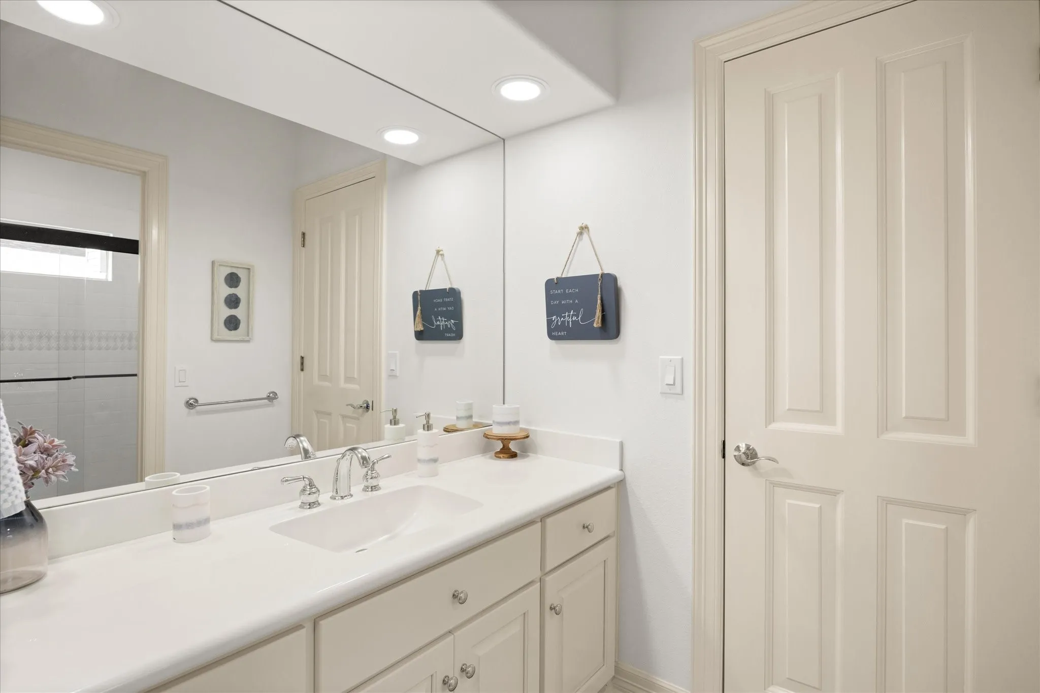 White bathroom vanity with dual integrated sinks, chrome fixtures, and under-counter cabinetry