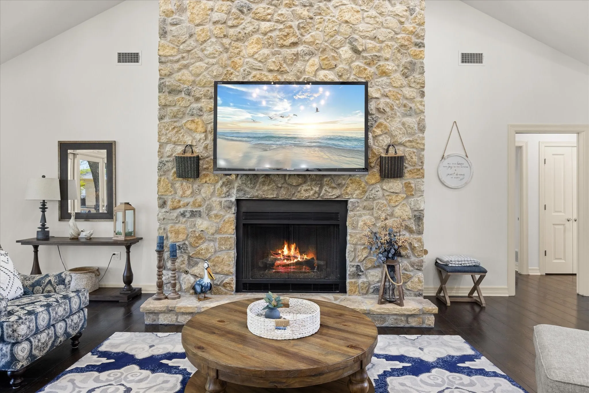 Stone-clad fireplace with a raised hearth, featuring a dark firebox and dark wood-finish flooring