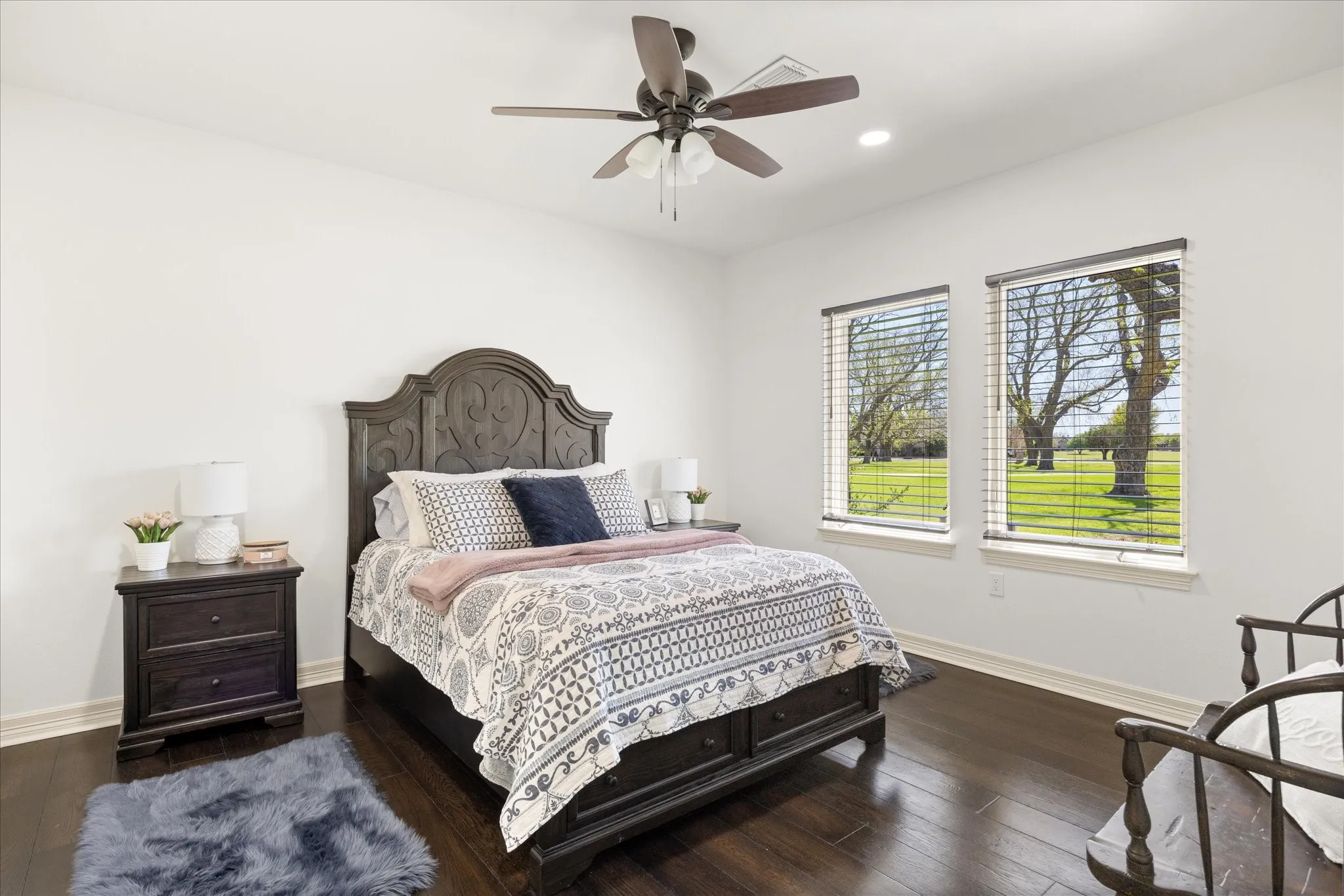Bedroom featuring dark wood-finish flooring, white walls, and a ceiling fan with integrated lighting
