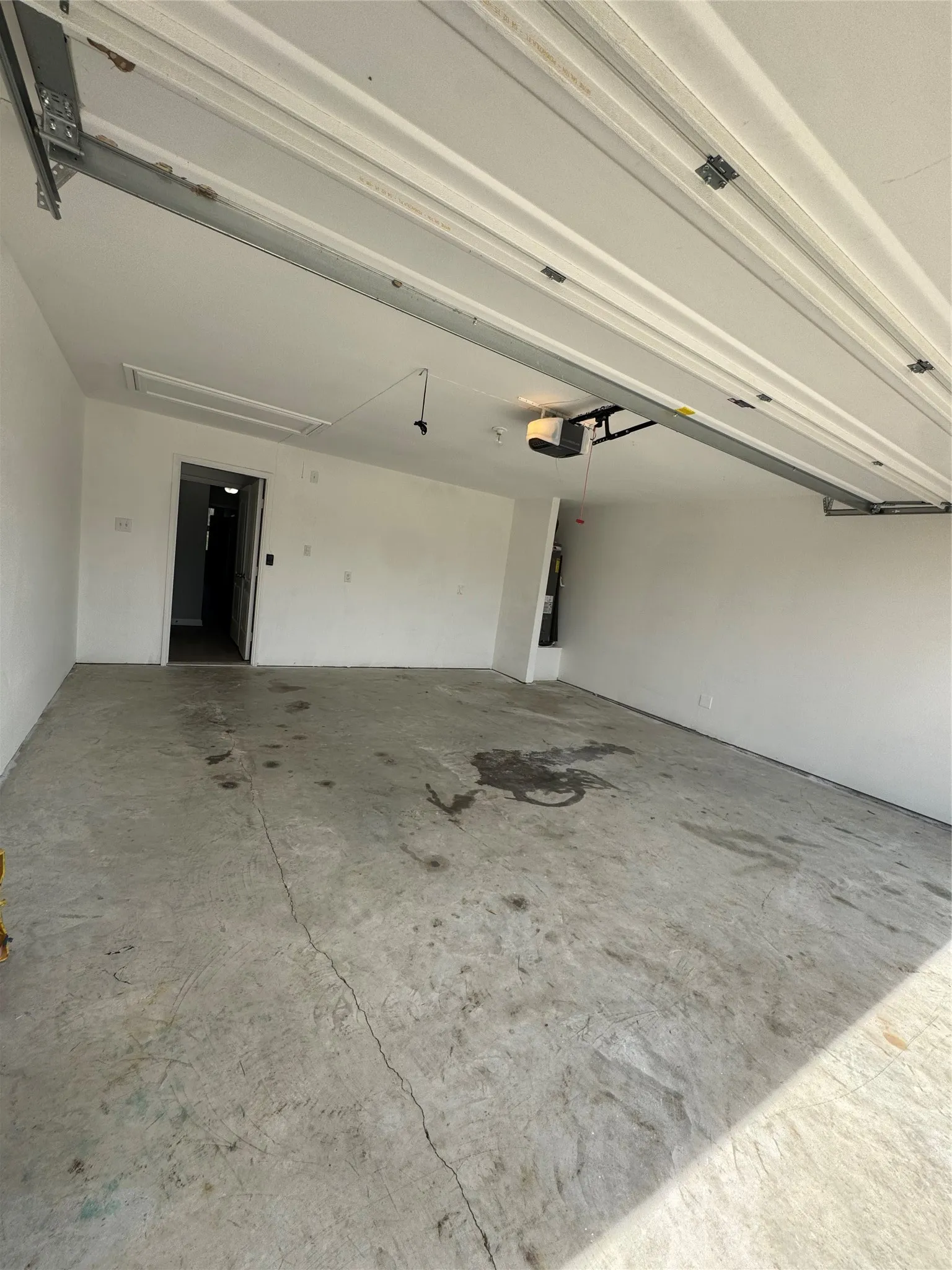 Spacious garage with concrete flooring, white painted walls, and an automatic garage door opener