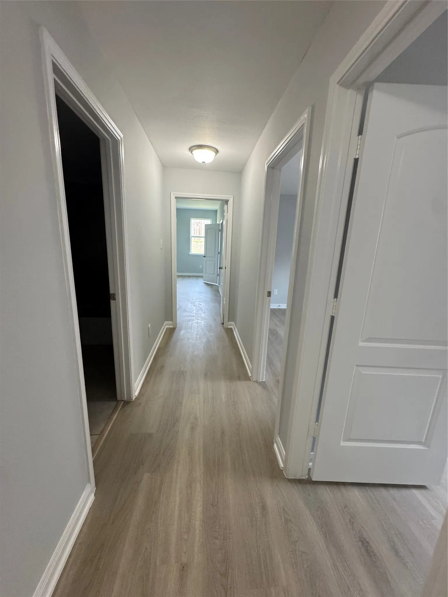 Hallway featuring wood-finish flooring, light gray wall paint, white trim, and a semi-flush mount ceiling light
