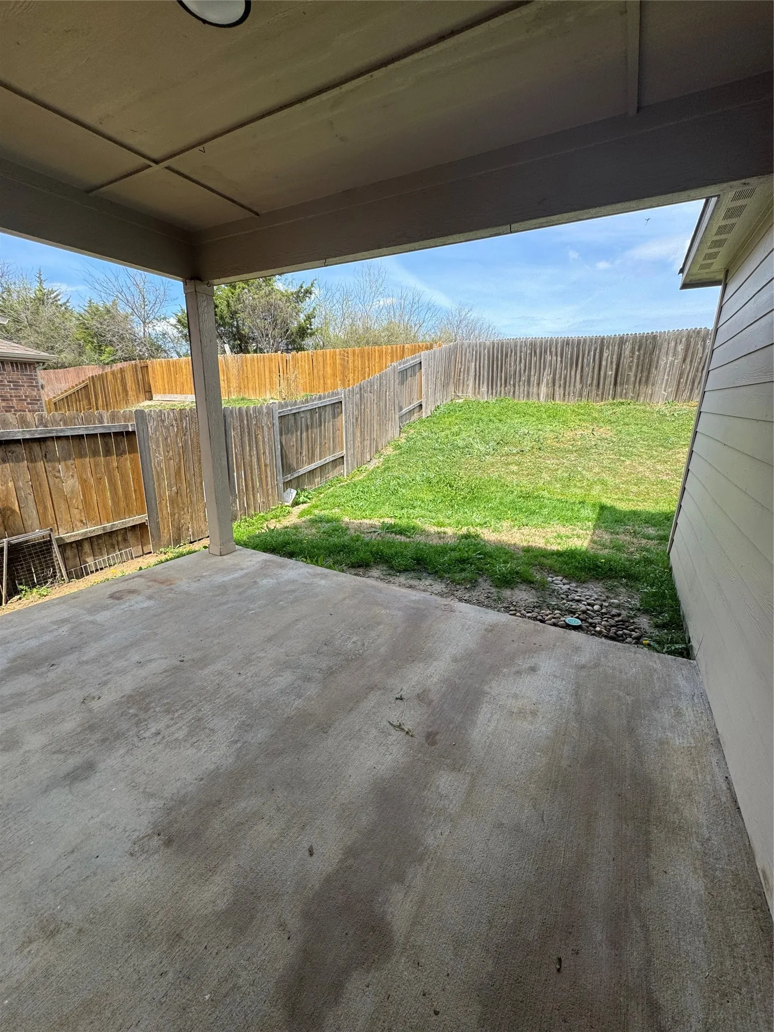 Covered patio with a concrete surface, providing a shaded outdoor area