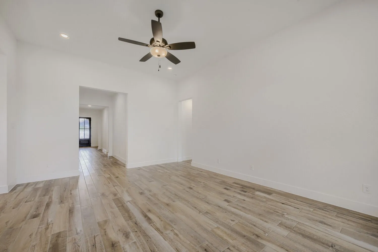 Spacious room featuring light wood-finish flooring, recessed lighting, and a ceiling fan with integrated light fixture
