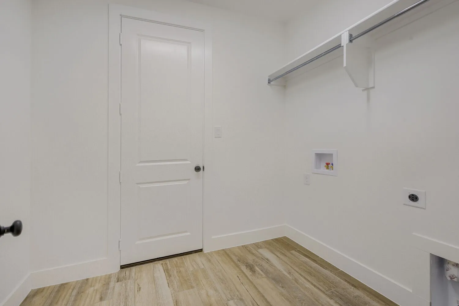 Utility room featuring wood-finish flooring, white walls, and a built-in hanging rod