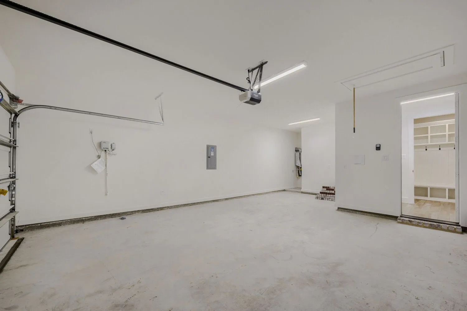 Spacious garage with an automatic door opener, concrete flooring, and bright overhead lighting