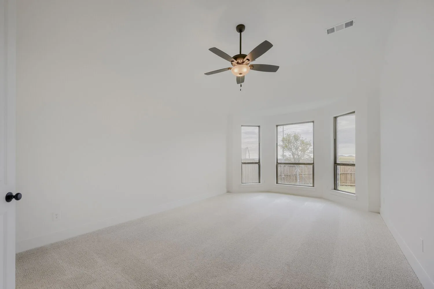 Expansive room featuring light-colored carpeting, white walls, and a multi-pane bay window