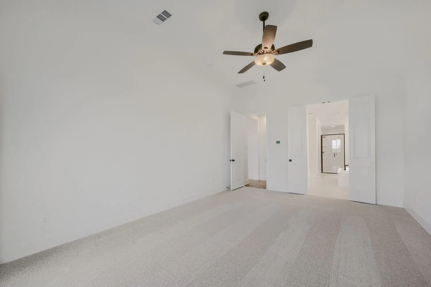 Spacious room featuring vaulted ceilings and light-colored carpeting