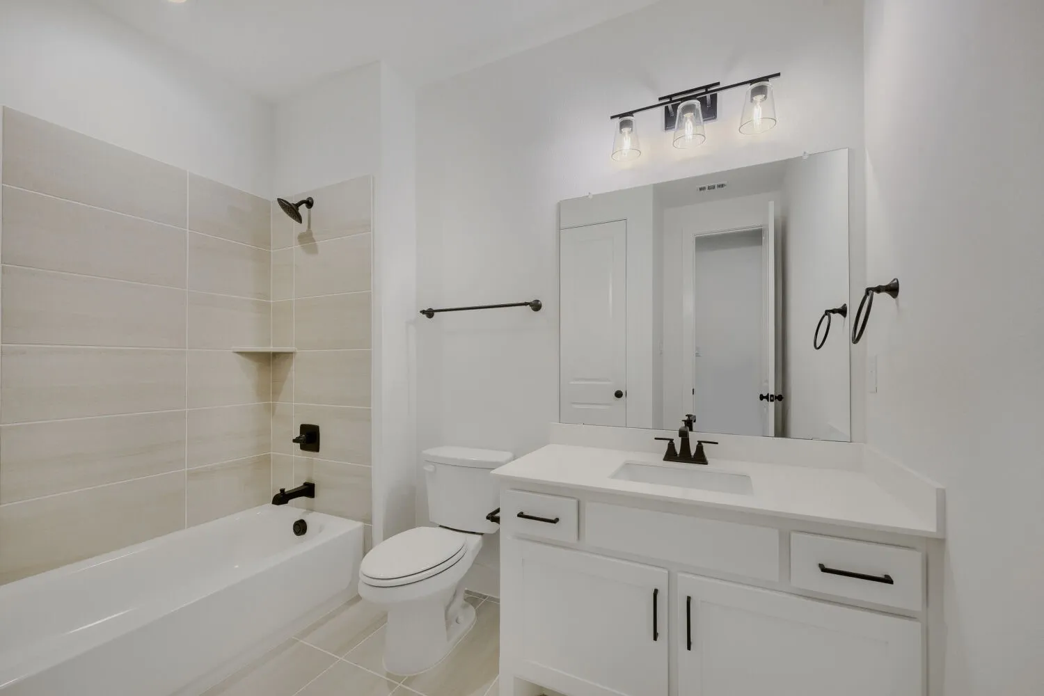 Modern bathroom featuring a white vanity with integrated sink, a large wall-mounted mirror, and a sleek three-light fixture