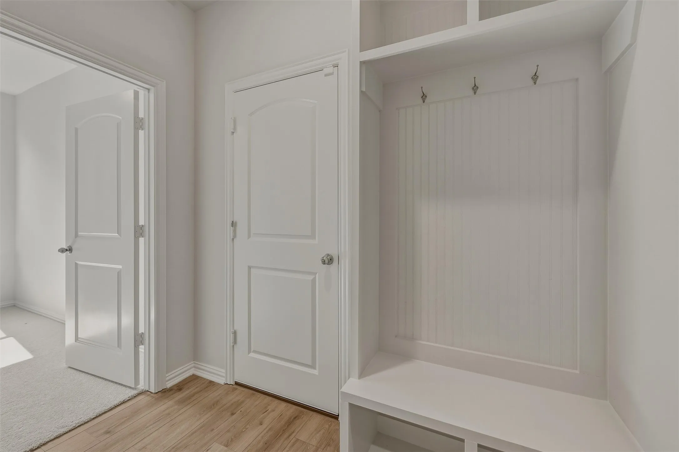 Built-in storage bench with beadboard backing and wall hooks