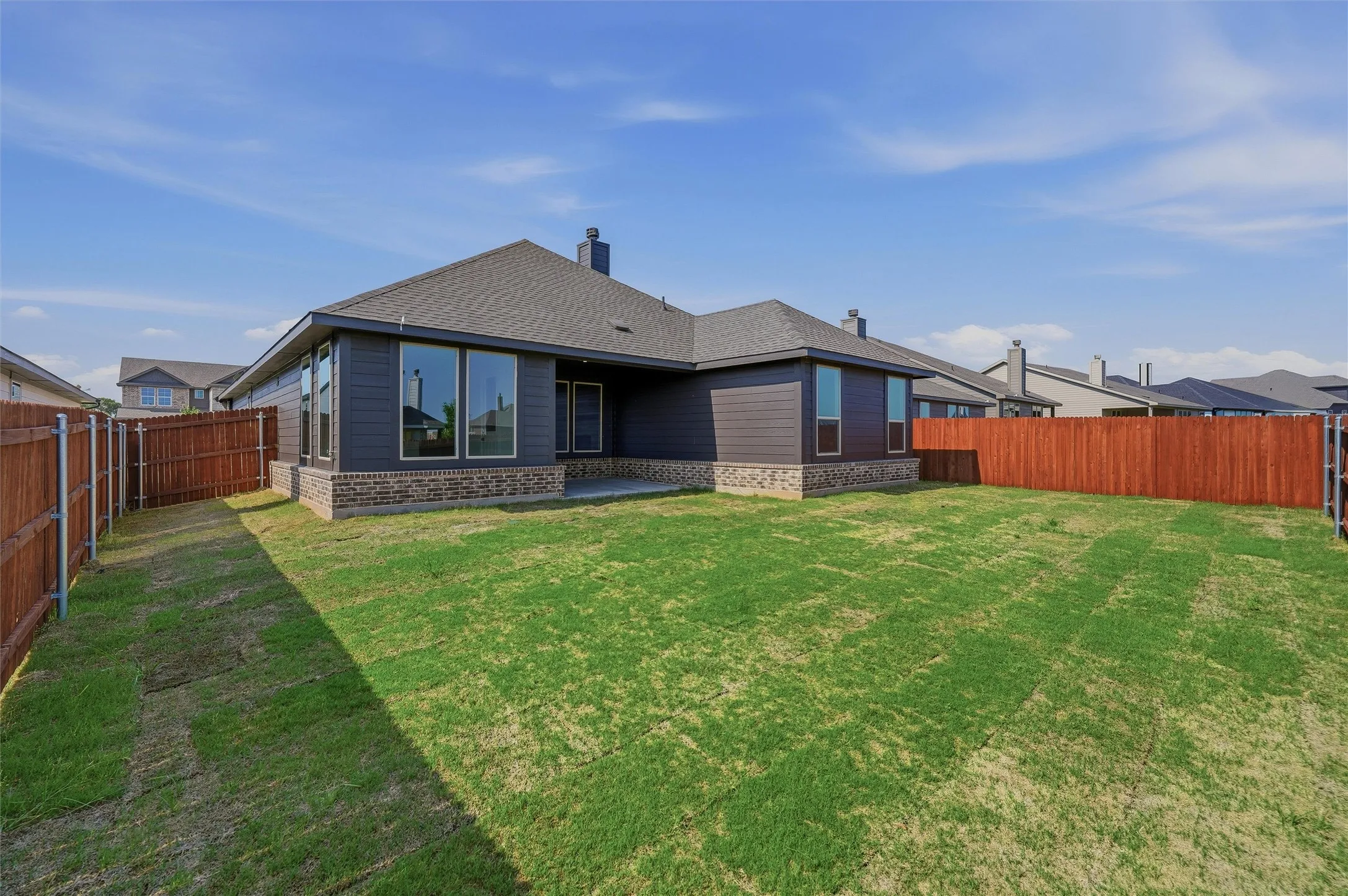 Expansive backyard with a manicured lawn, full privacy fencing, and a concrete patio