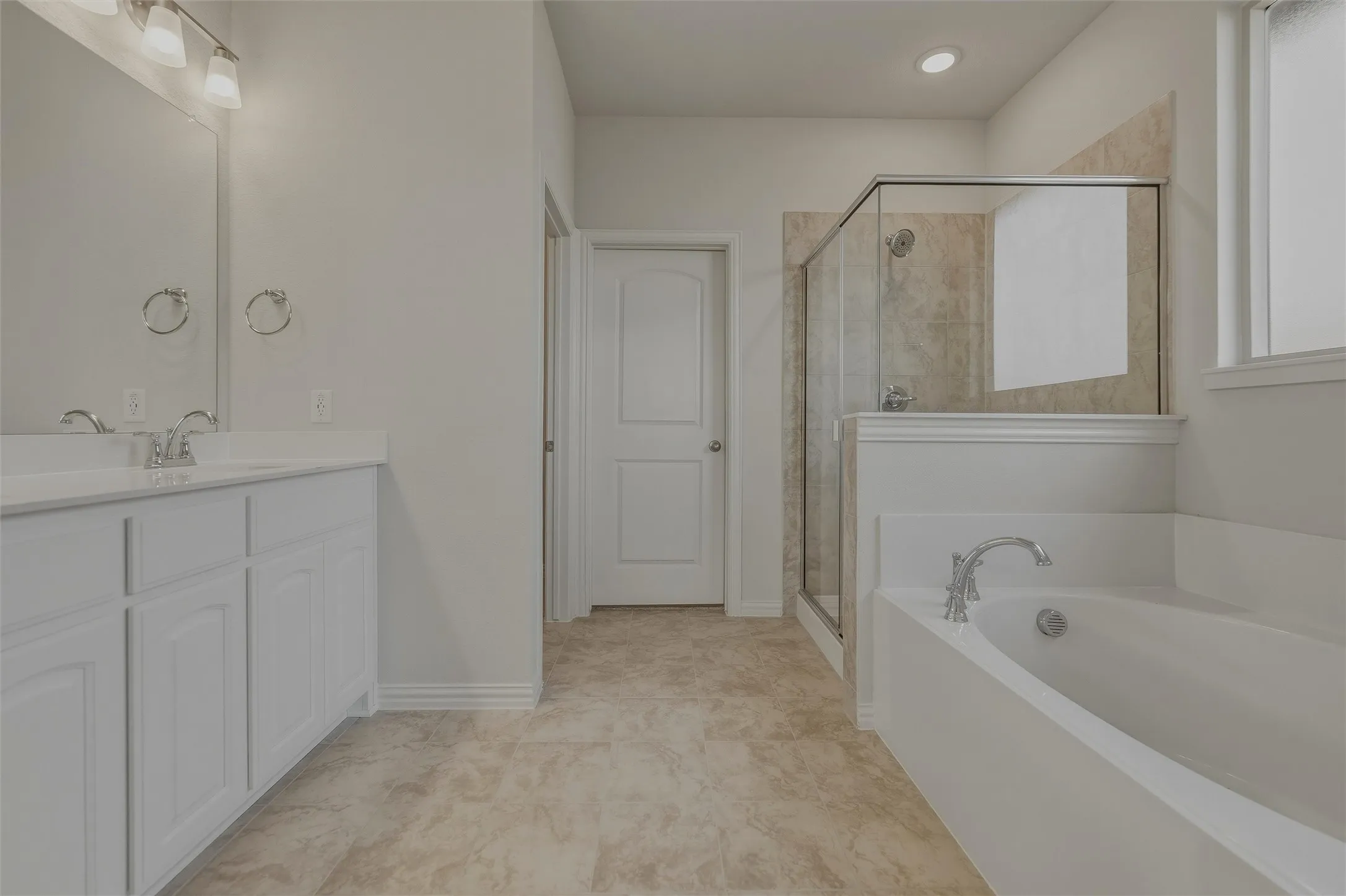 Dual vanity with white cabinetry, built-in bathtub, and a glass-enclosed shower featuring tiled walls