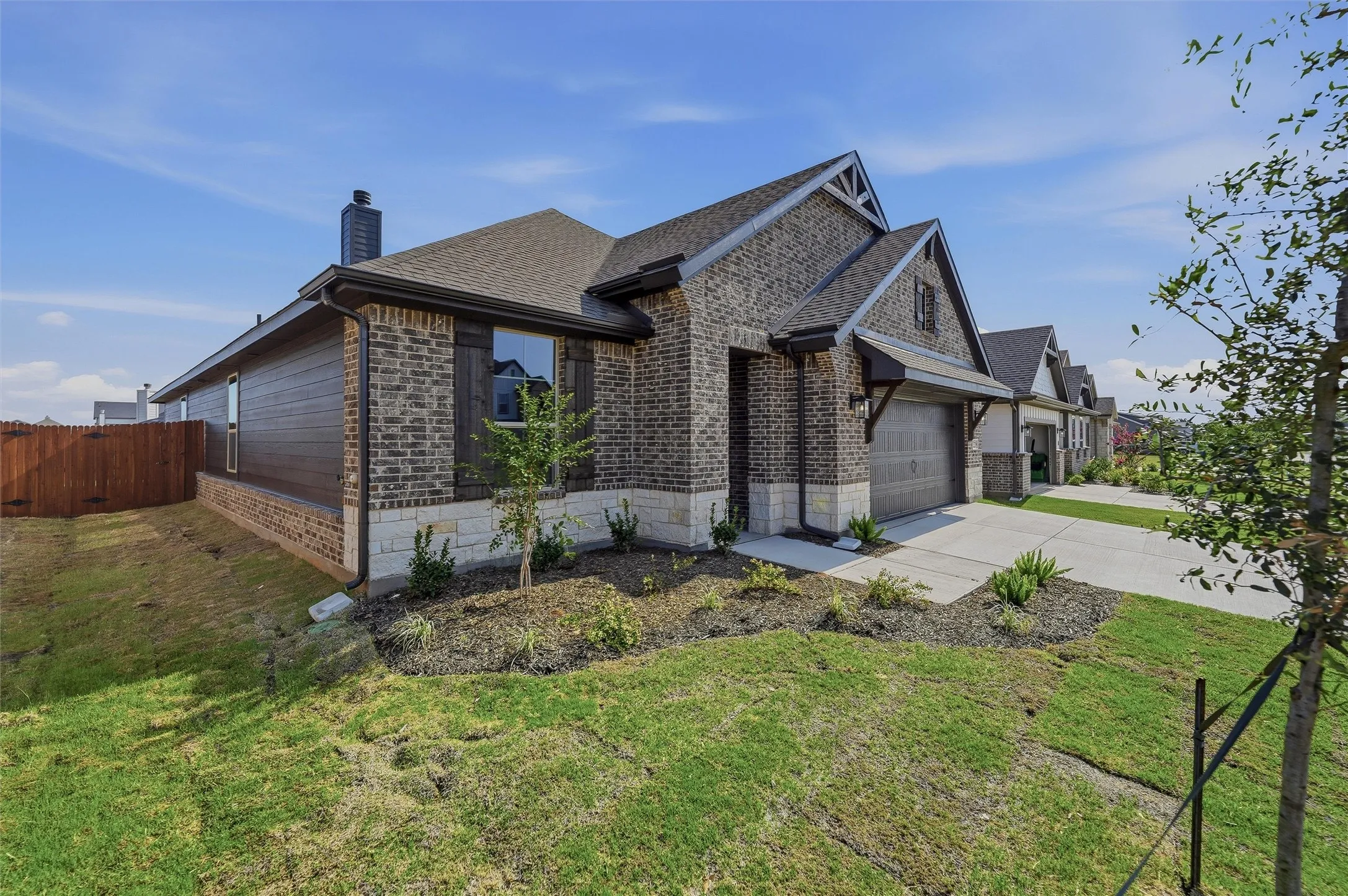 Brick and stone exterior with dark wood shutters and a two-car garage