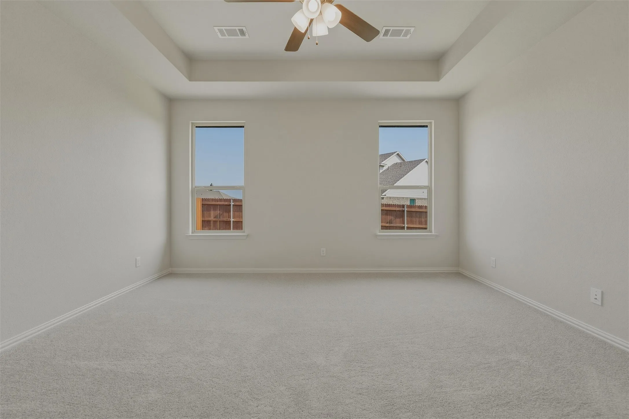 Recessed ceiling, ceiling fan, two windows, wall-to-wall carpeting, and light-toned walls