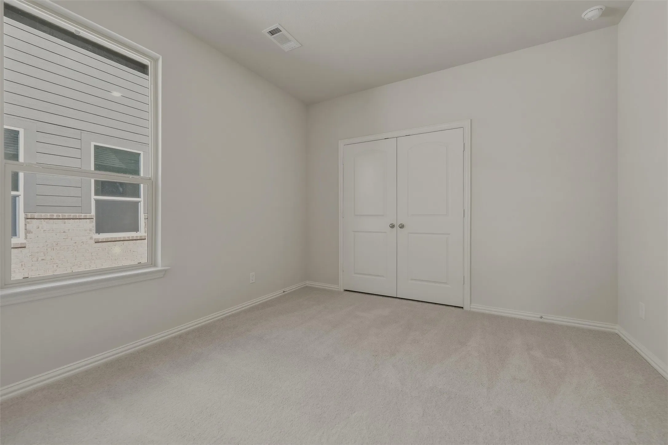 Neutral tone walls, light-toned carpeting, white trim, and a double-door closet