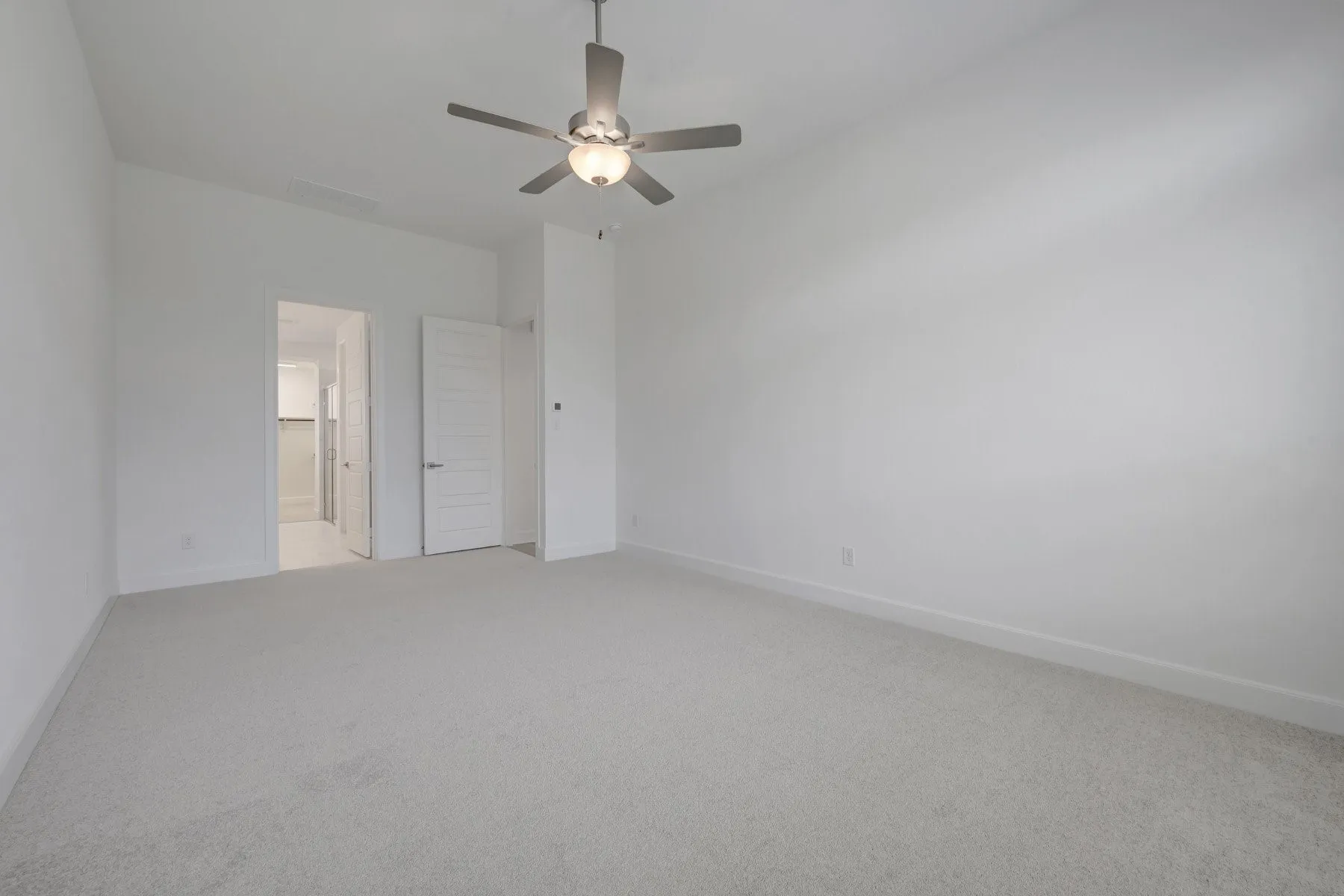 Spacious room with light neutral carpeting and white painted walls
