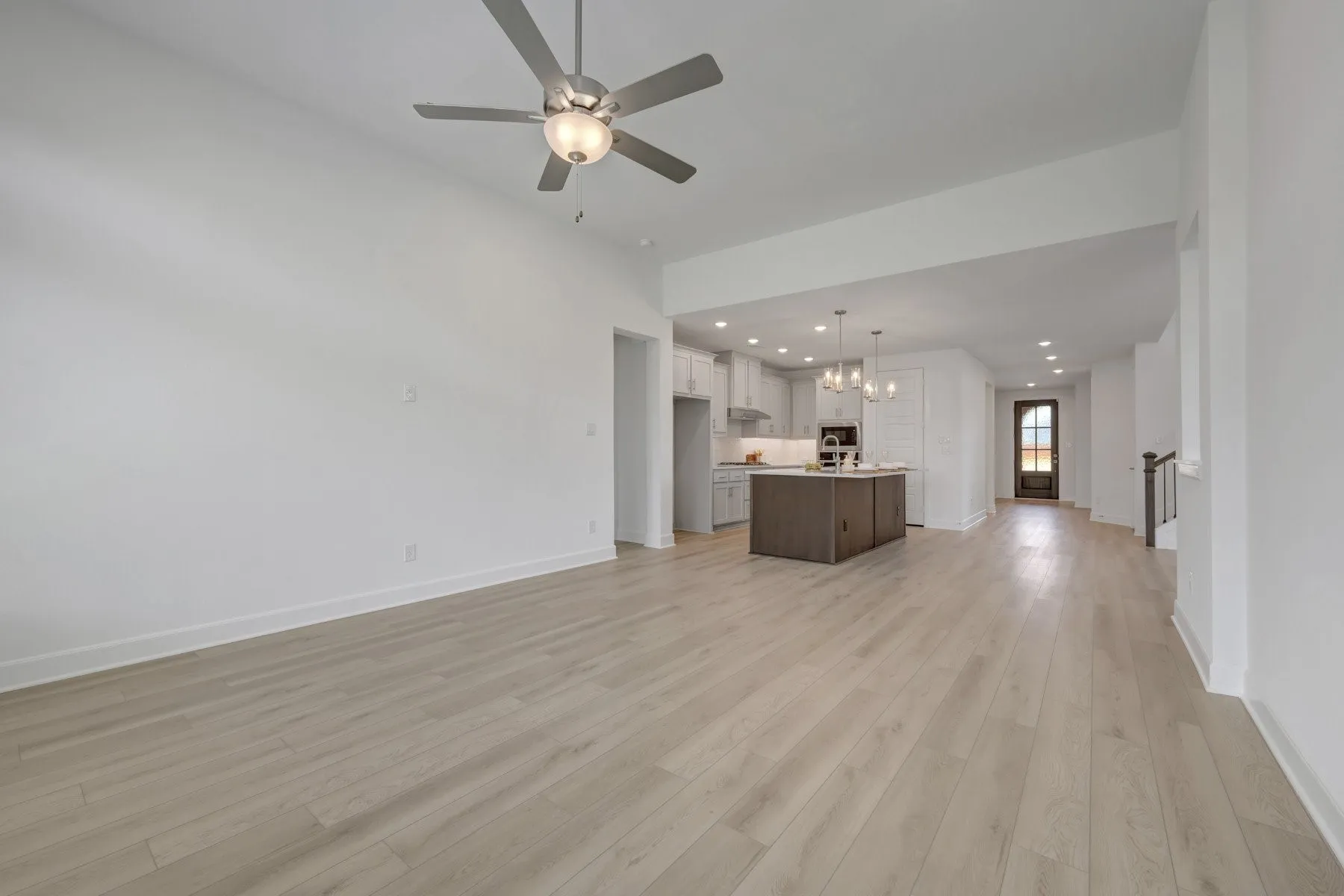 Spacious open concept living area featuring light wood-finish flooring, recessed lighting, and a modern ceiling fan