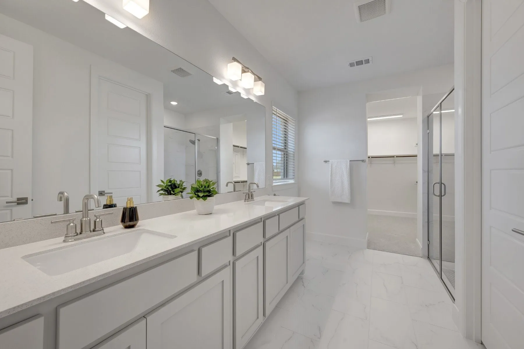 Dual sink vanity featuring light-toned countertops and under-sink cabinetry