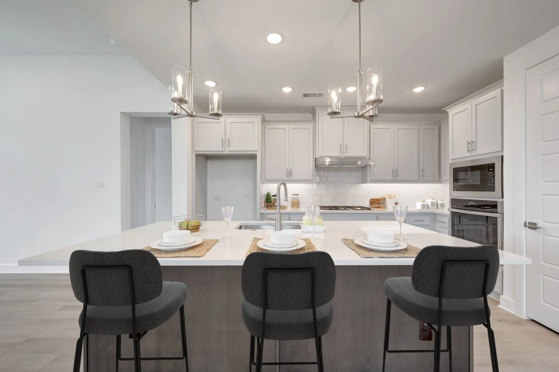 Kitchen featuring a spacious island with light-toned countertop, white cabinetry with hardware, stainless steel appliances, a tile backsplash, and recessed lighting
