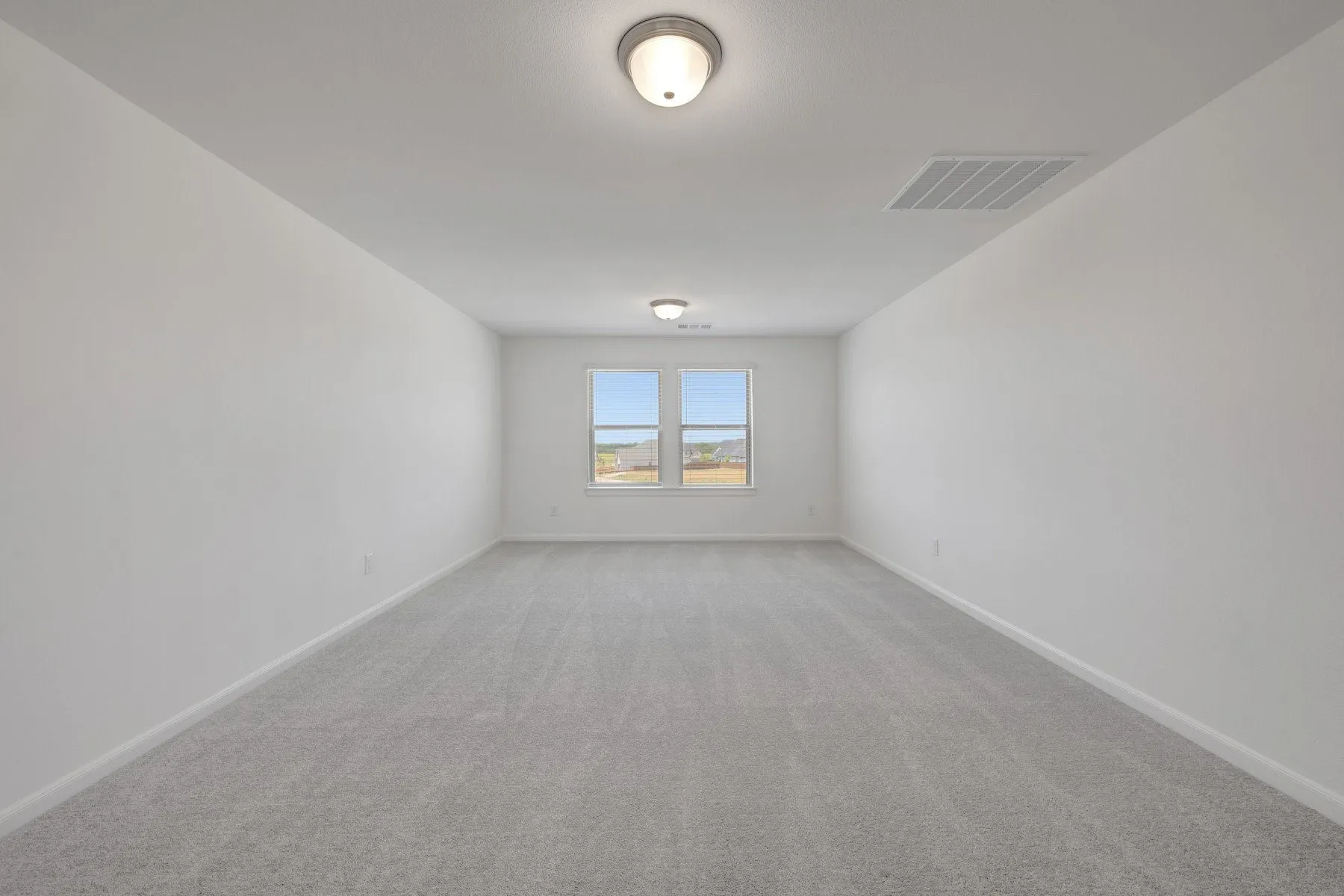 Expansive room featuring light gray carpeting and white painted walls