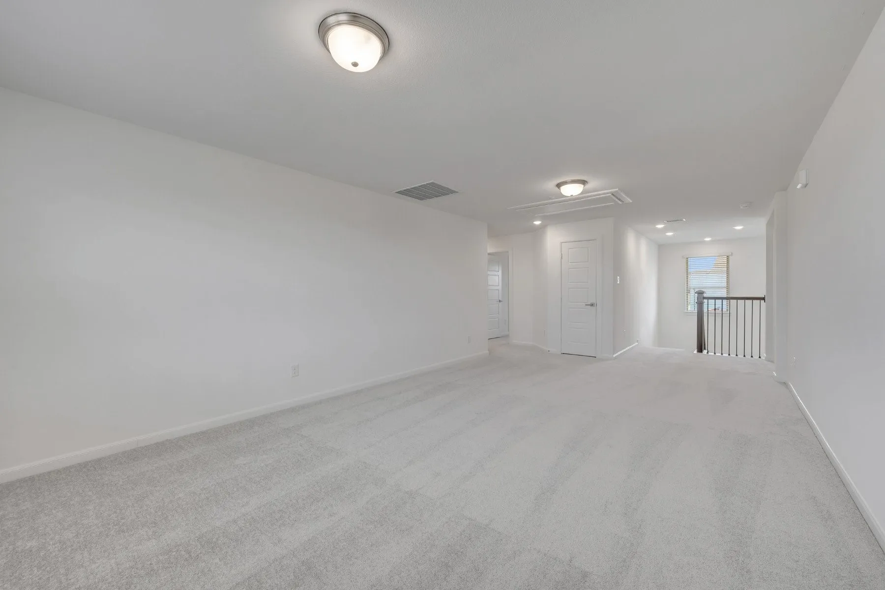 Spacious open-concept room featuring neutral-tone carpet flooring, recessed ceiling lighting, and clean white walls