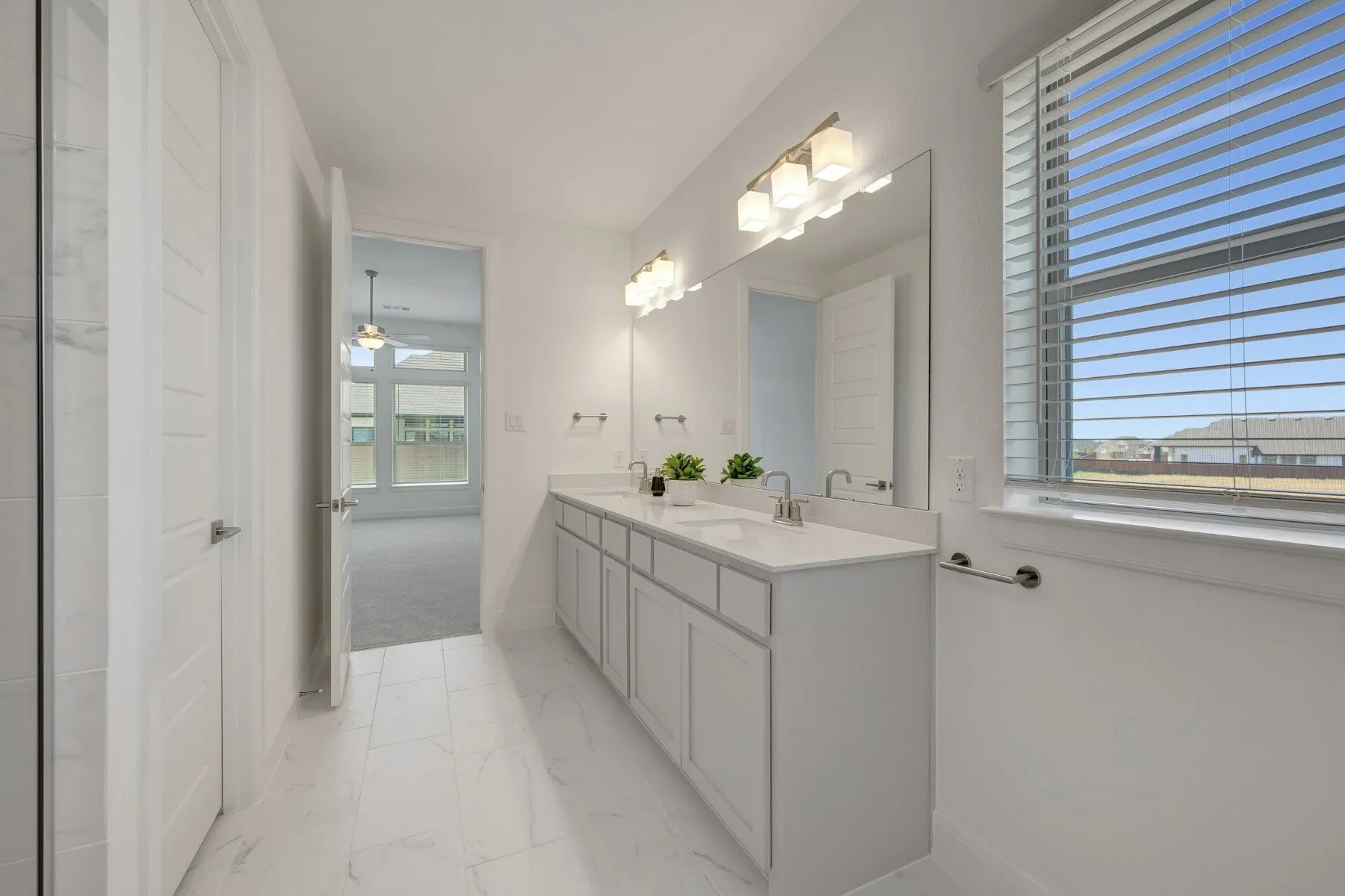Spacious bathroom featuring a dual vanity with white cabinetry, a large mirror, and contemporary light fixtures