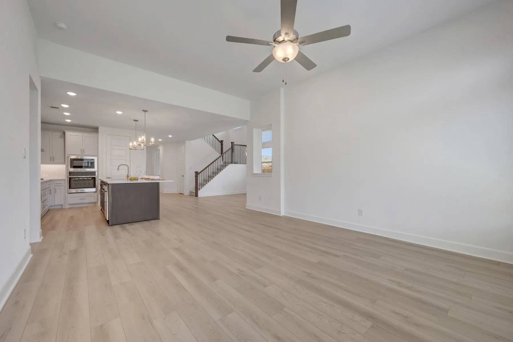 Open concept living area featuring light wood-finish flooring and a ceiling fan