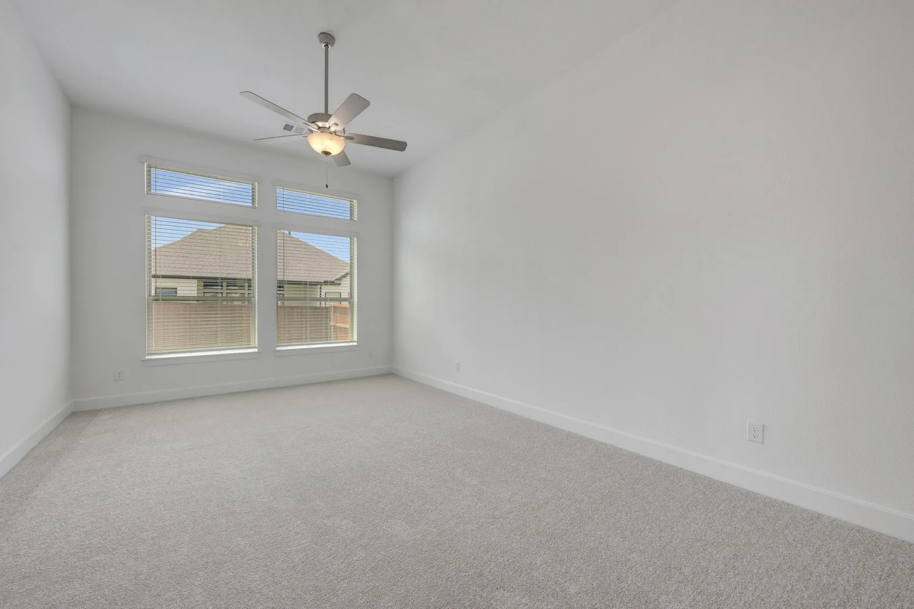 Spacious room featuring multiple windows with horizontal blinds, providing ample natural light
