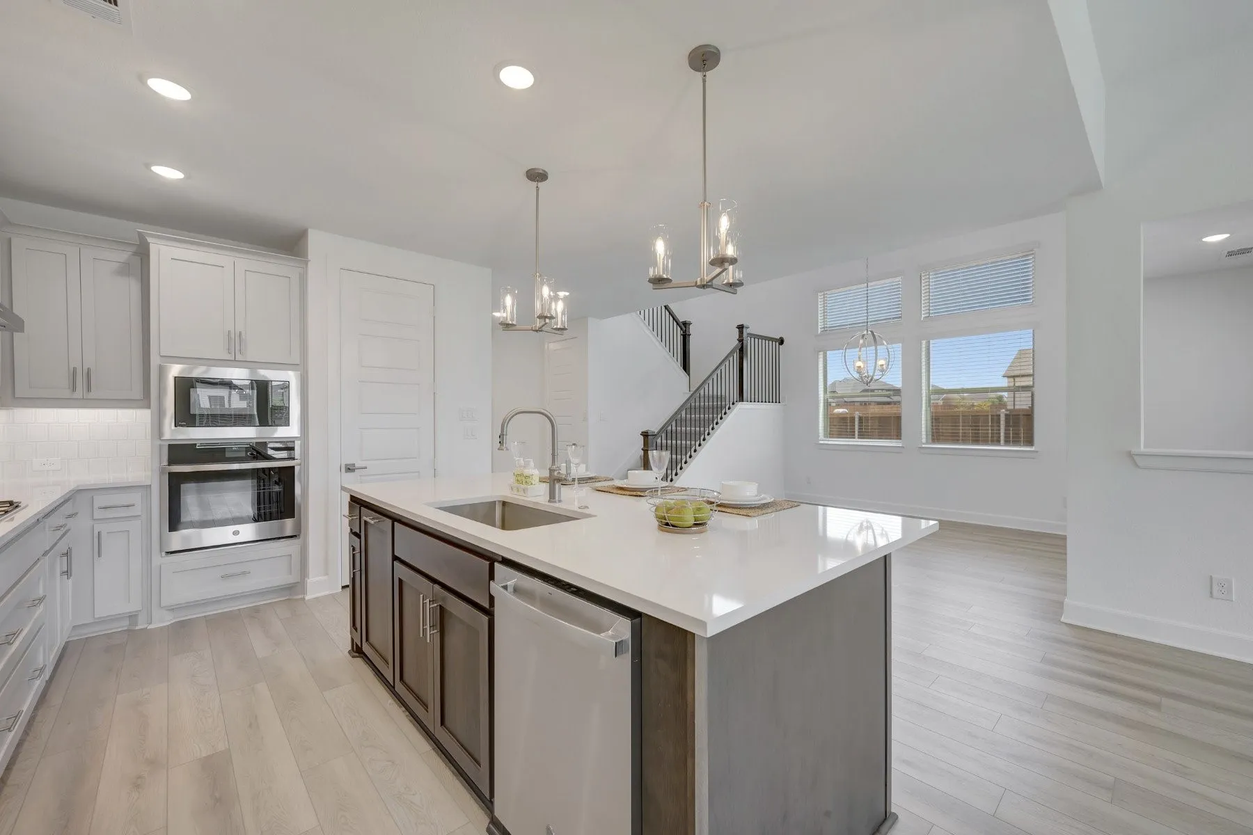 Kitchen island featuring a stainless steel sink, integrated dishwasher, and a white countertop