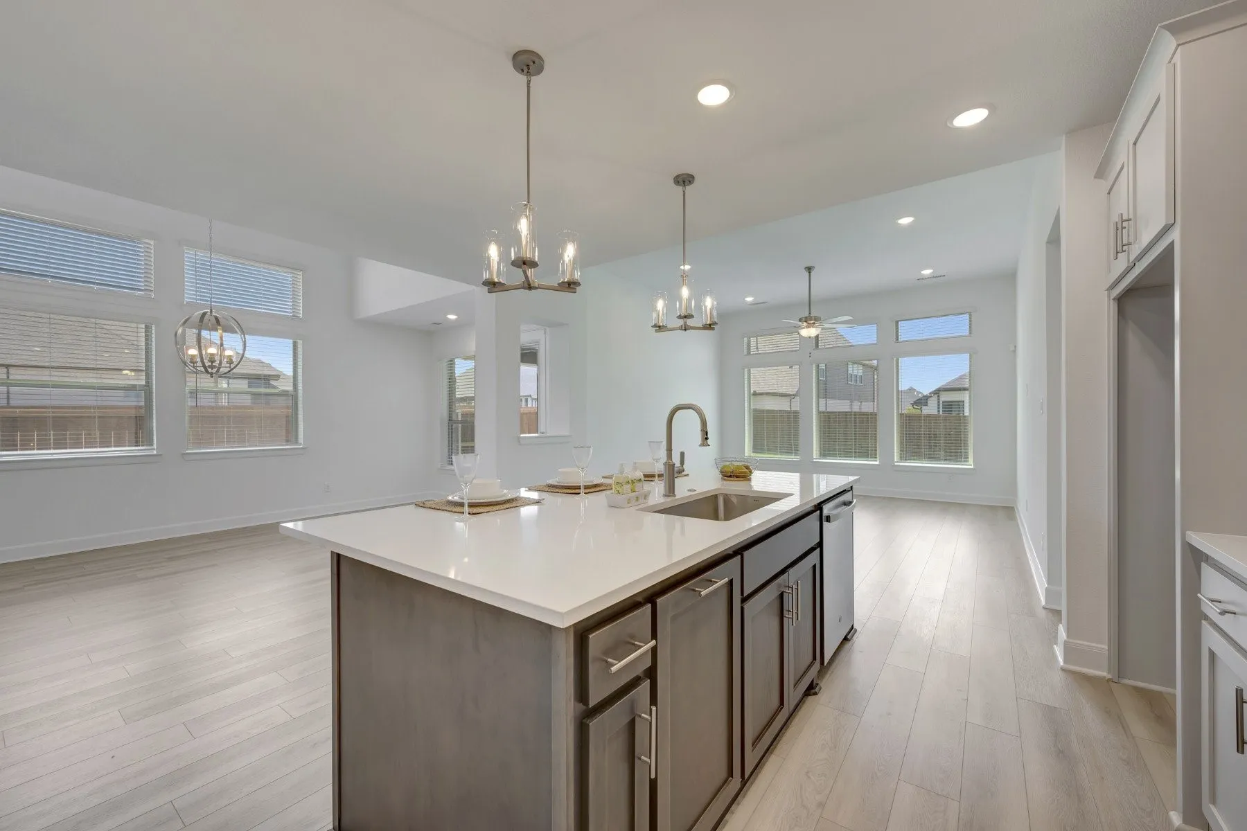 Bright and spacious kitchen showcasing a large center island with wood-finish cabinetry, white quartz countertops, and an undermount sink with contemporary faucet