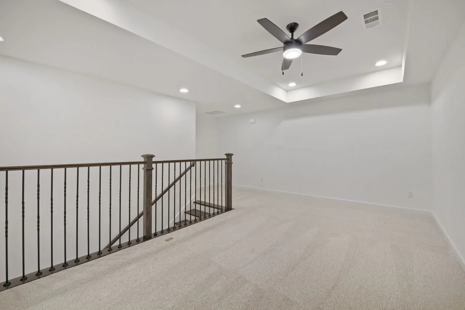 Carpeted loft area featuring a tray ceiling with recessed lighting and a ceiling fan