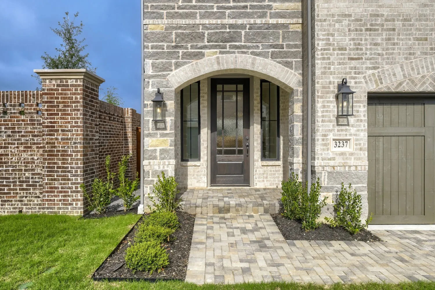 Front entrance featuring an arched portico, a dark wood-finish door with glass inserts, and flanking vertical windows