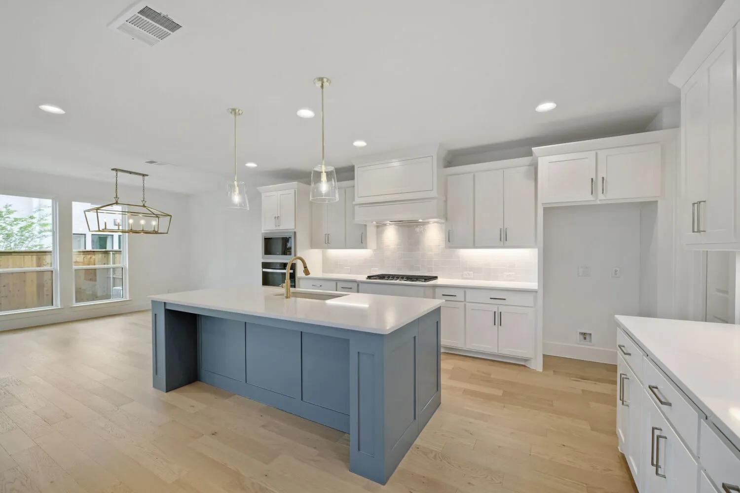 Modern kitchen featuring a blue-toned island with a white countertop and brass-finish faucet