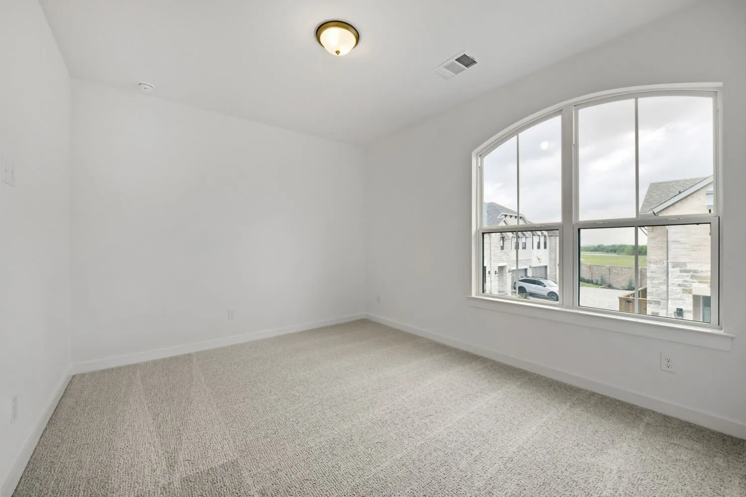Room featuring an arched window, light-toned carpet, white painted walls, and a ceiling-mounted light fixture