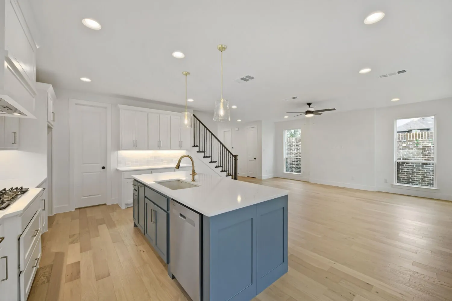 Open-concept living area with wood-finish flooring, recessed lighting, and a contemporary ceiling fan